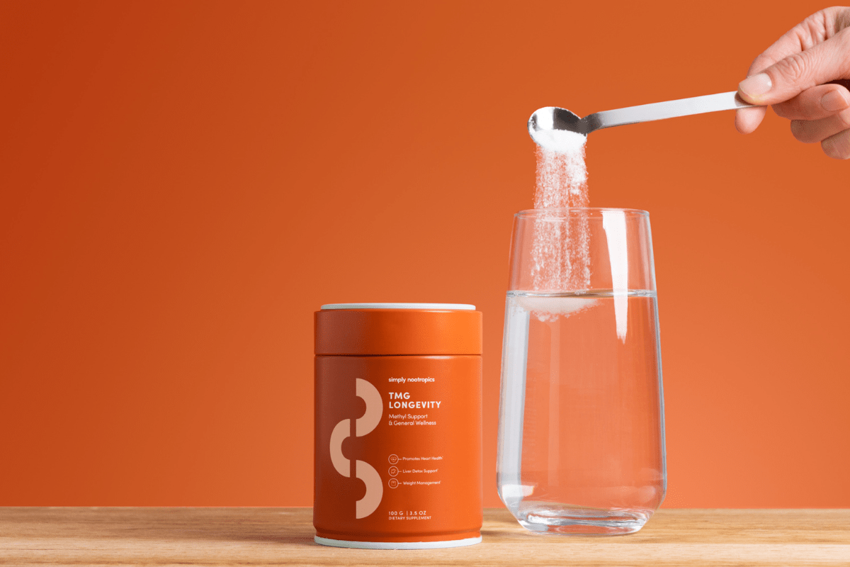 TMG supplement powder being poured into a glass of water.