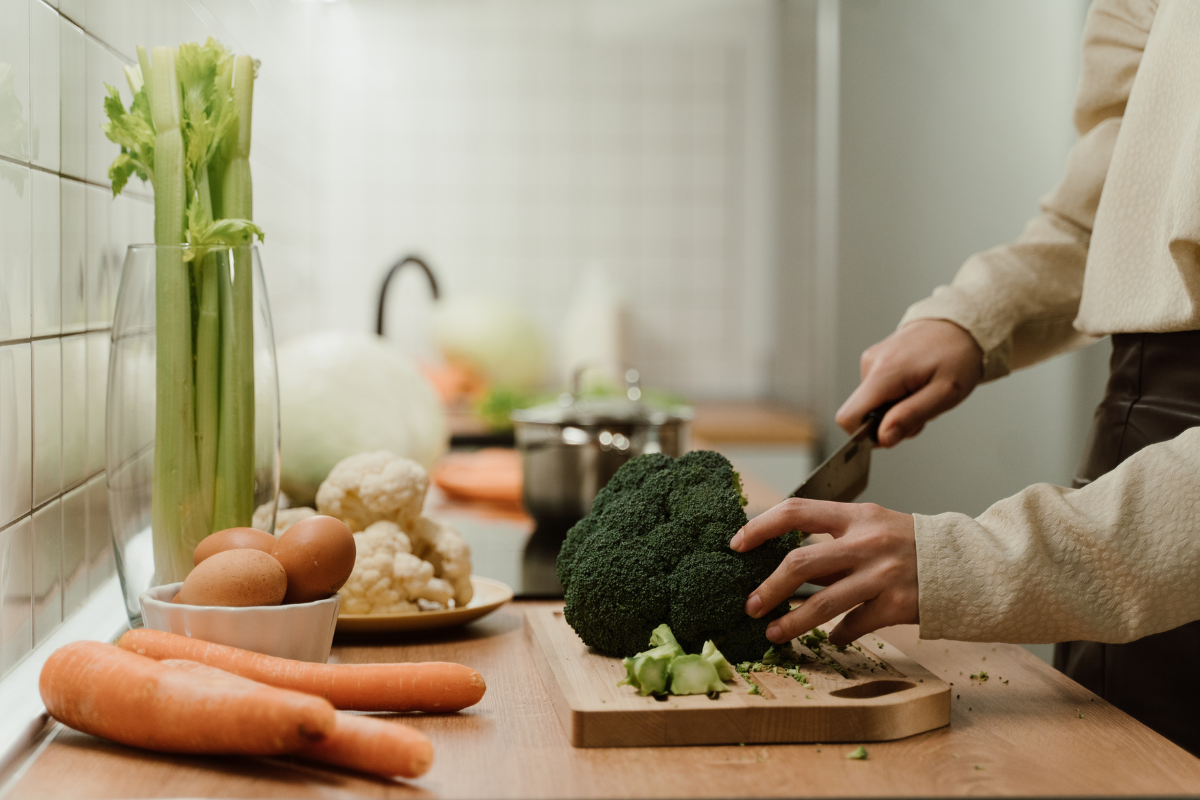 Person chopping fresh broccoli in a kitchen.