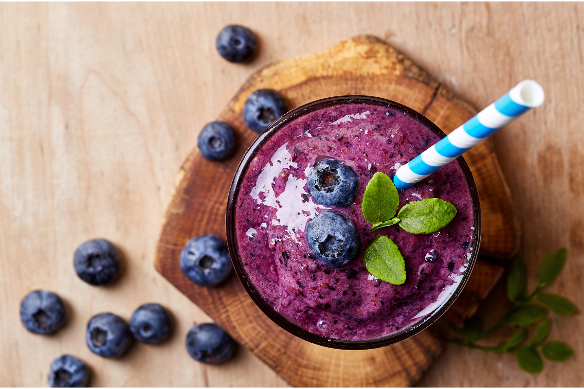 Berry smoothie in a glass with a straw.