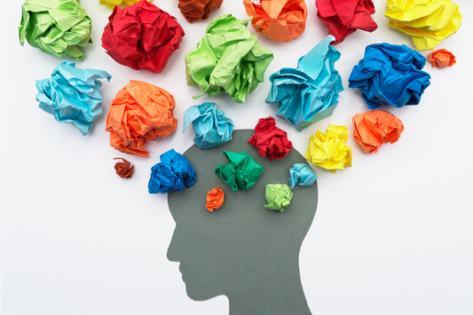 Silhouette of a person's head surrounded by colorful paper pieces arranged like scattered thoughts.