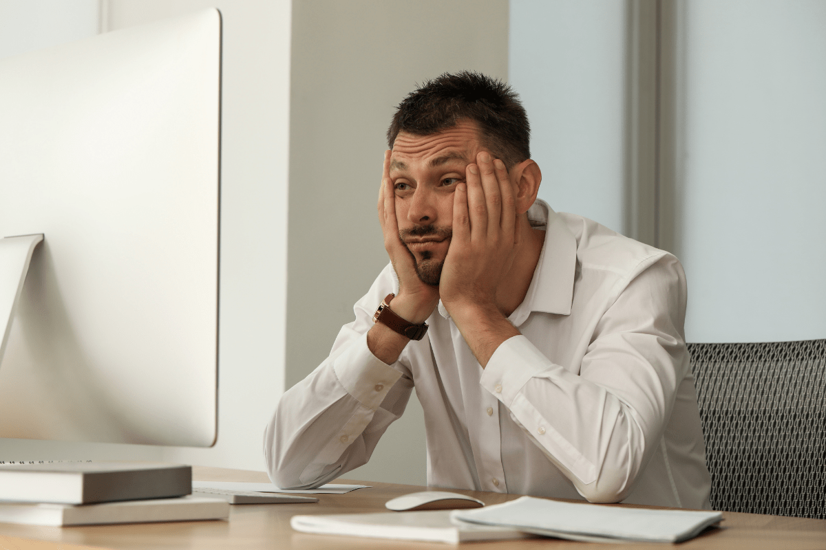 Tired man in office clothes holding his face with both hands.