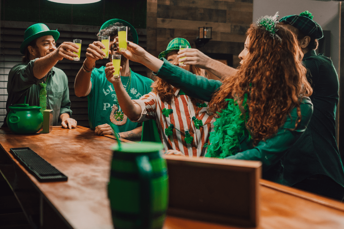 Group of friends dressed in green celebrating St. Patrick’s Day at a bar.