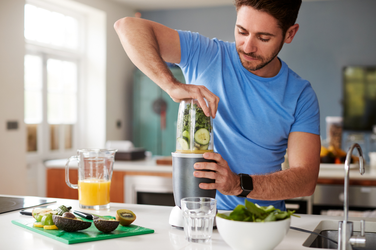 Man making a green smoothie in kitchen.