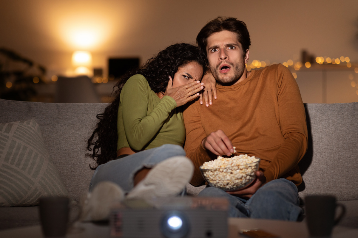 Couple reacting fearfully while watching a horror movie.