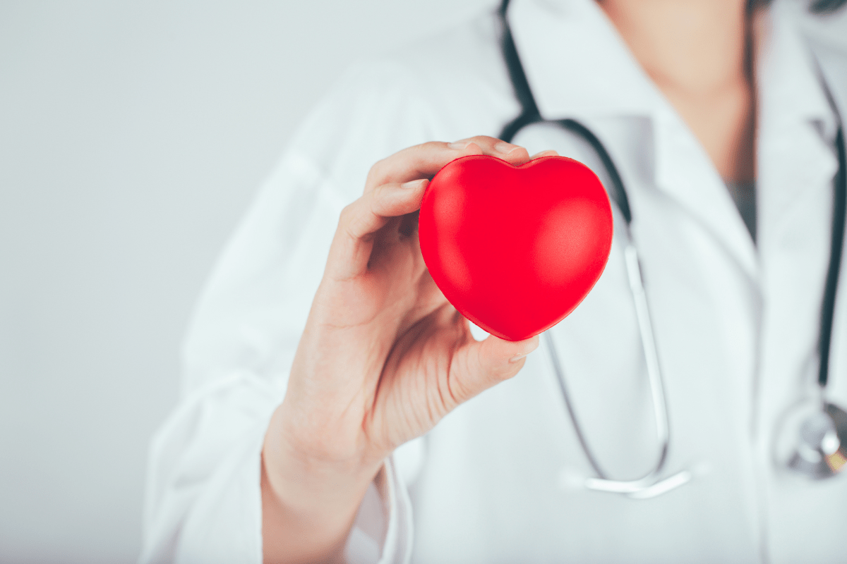 Doctor holding a red heart model, symbolizing heart health and medical advancements in cardiac care.