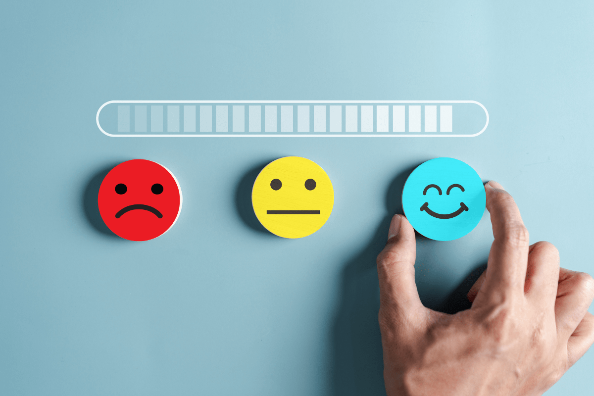 Hand selecting a smiling face emoji on a scale, symbolizing improved mood and stress relief.