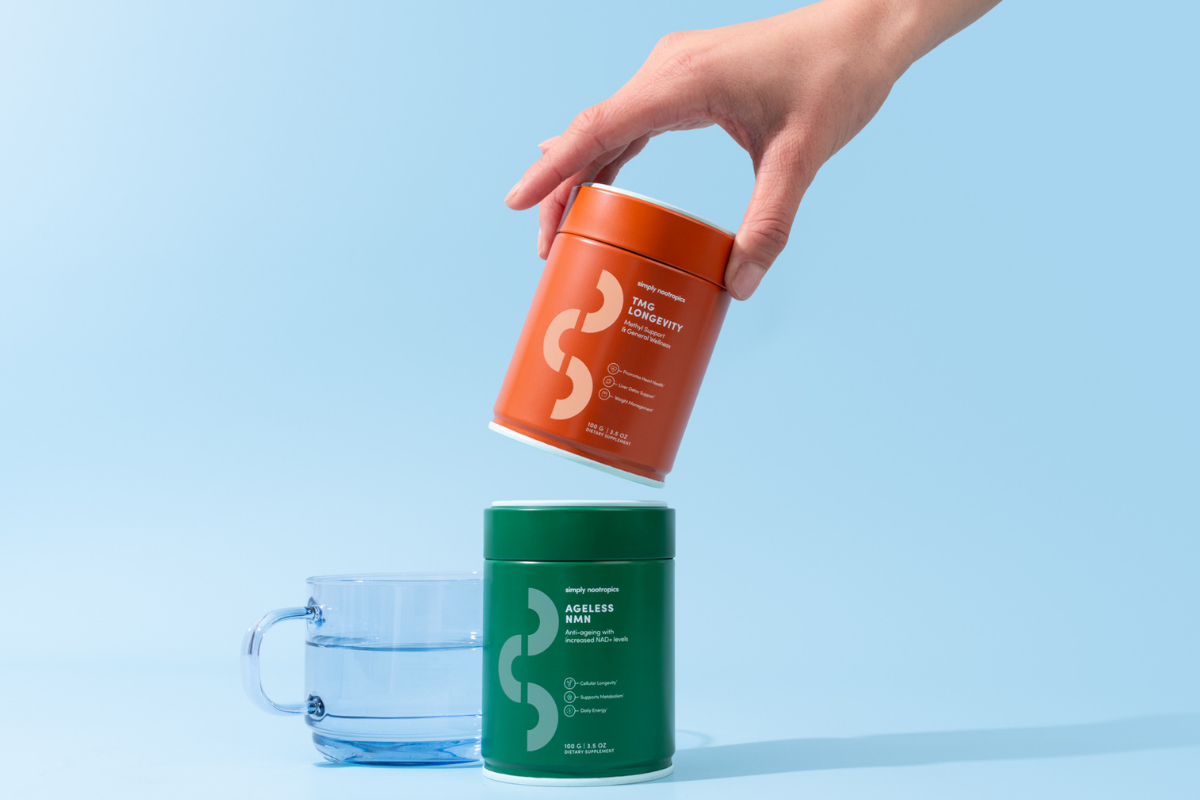 Hand stacking Simply Nootropics TMG Longevity and Ageless NMN powder tins.