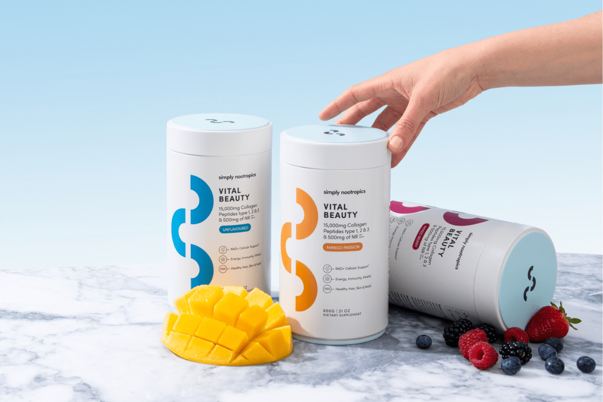 Collagen supplement containers with fresh mango and berries on a marble surface.