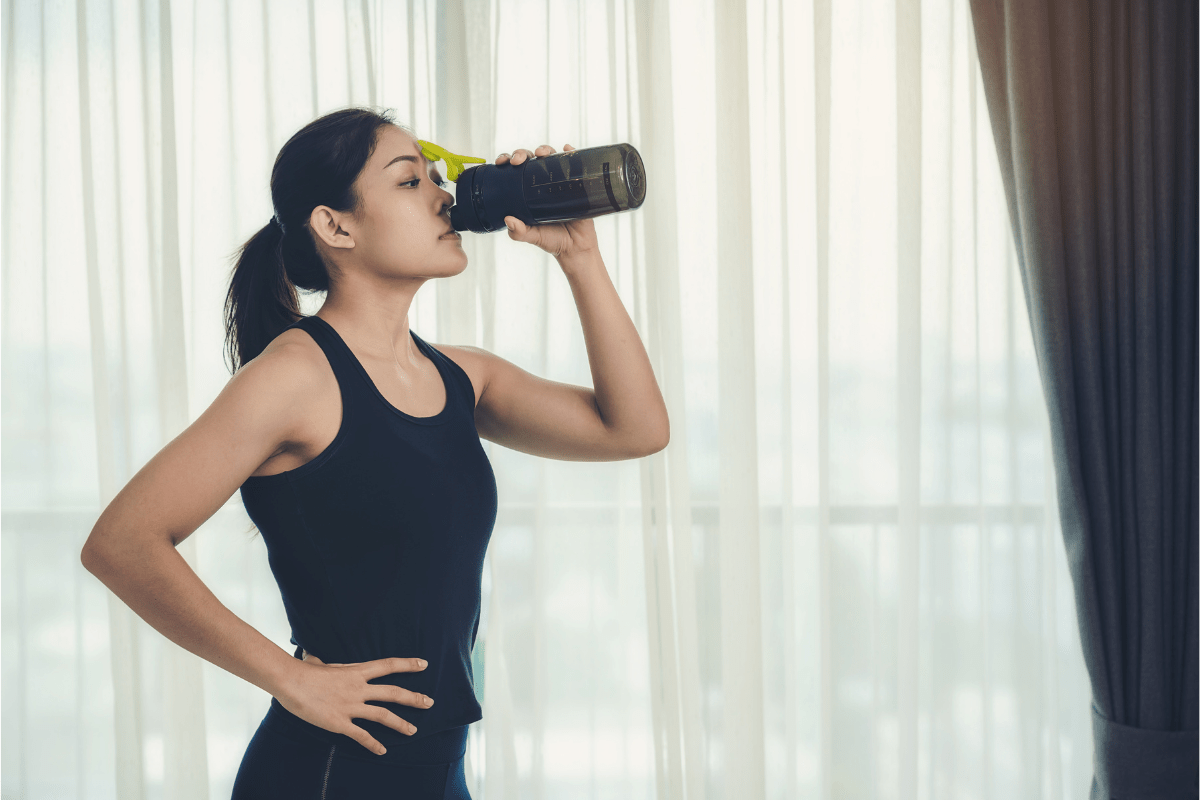 Woman in workout clothes drinking a post-exercise smoothie.
