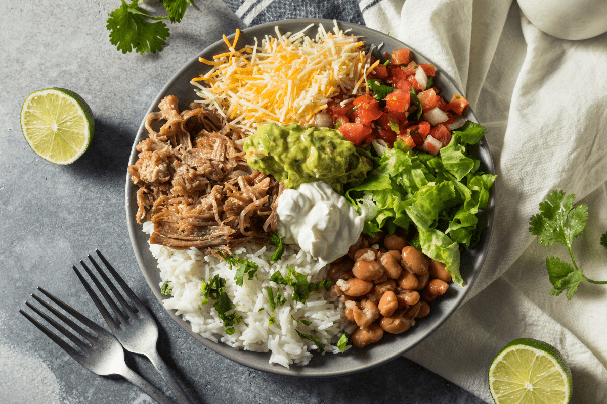 Colourful burrito bowl with rice, shredded meat and beans.