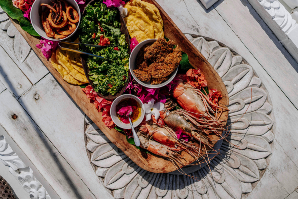 Seafood platter with prawns, dips, salads, and flatbreads on a wooden board.